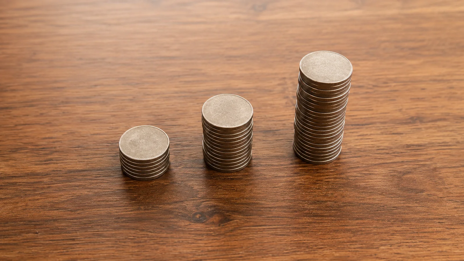 Three stacked piles of coins increasing in height, representing tiered pricing
